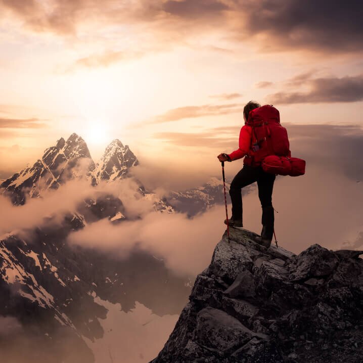 Mensch auf Bergspitze bei Sonnenaufgang